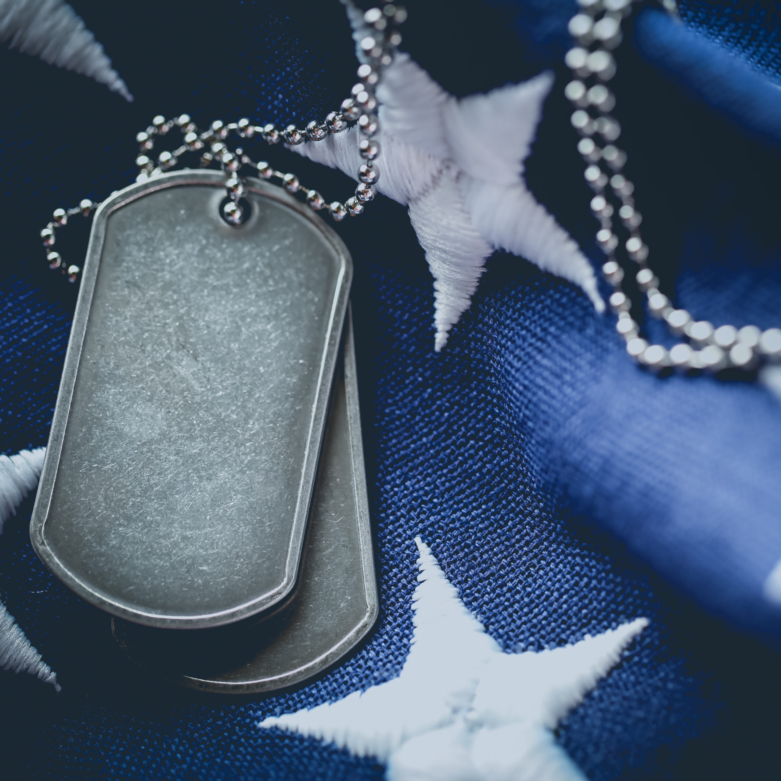 Worn USA military dog tags close up on US American flag with blank space for text