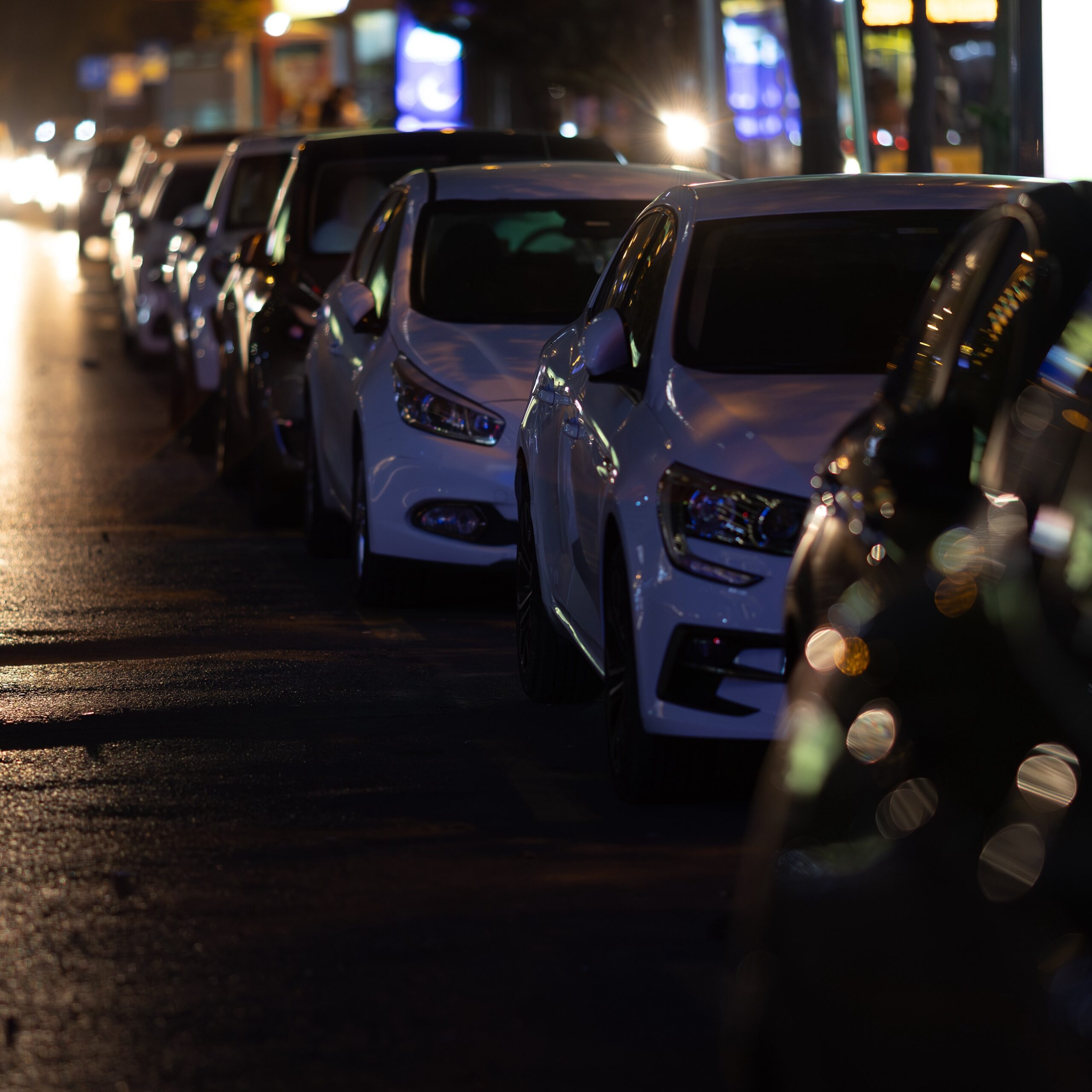 Cars standing in a row at night in parking. Urban street.