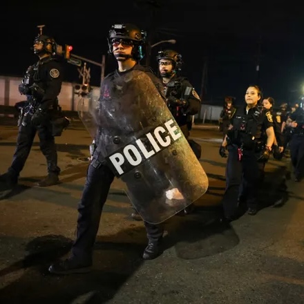 A group of police officers, one with a riot shield