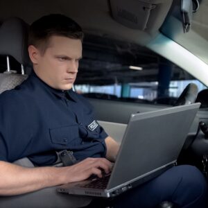 Policeman working on laptop in patrol car
