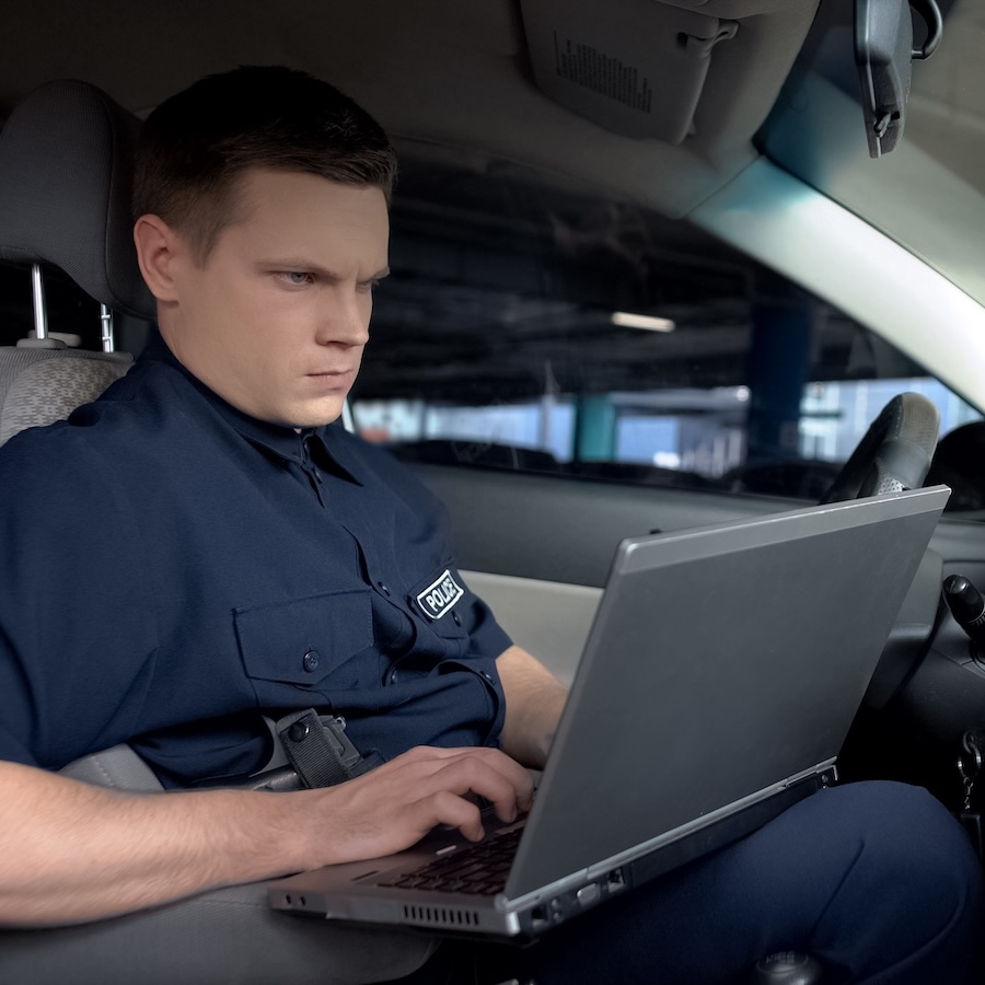 Policeman working on laptop in patrol car